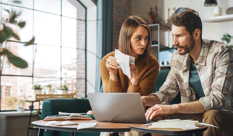 Couple reviewing finances with laptop and papers.