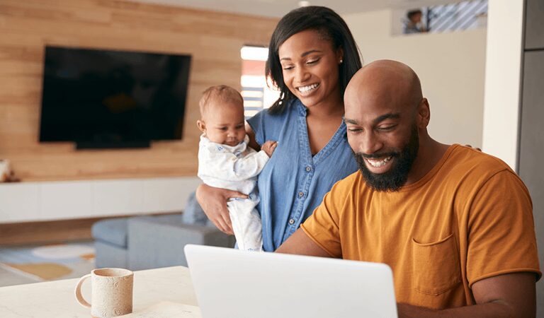 Smiling family using laptop at home.