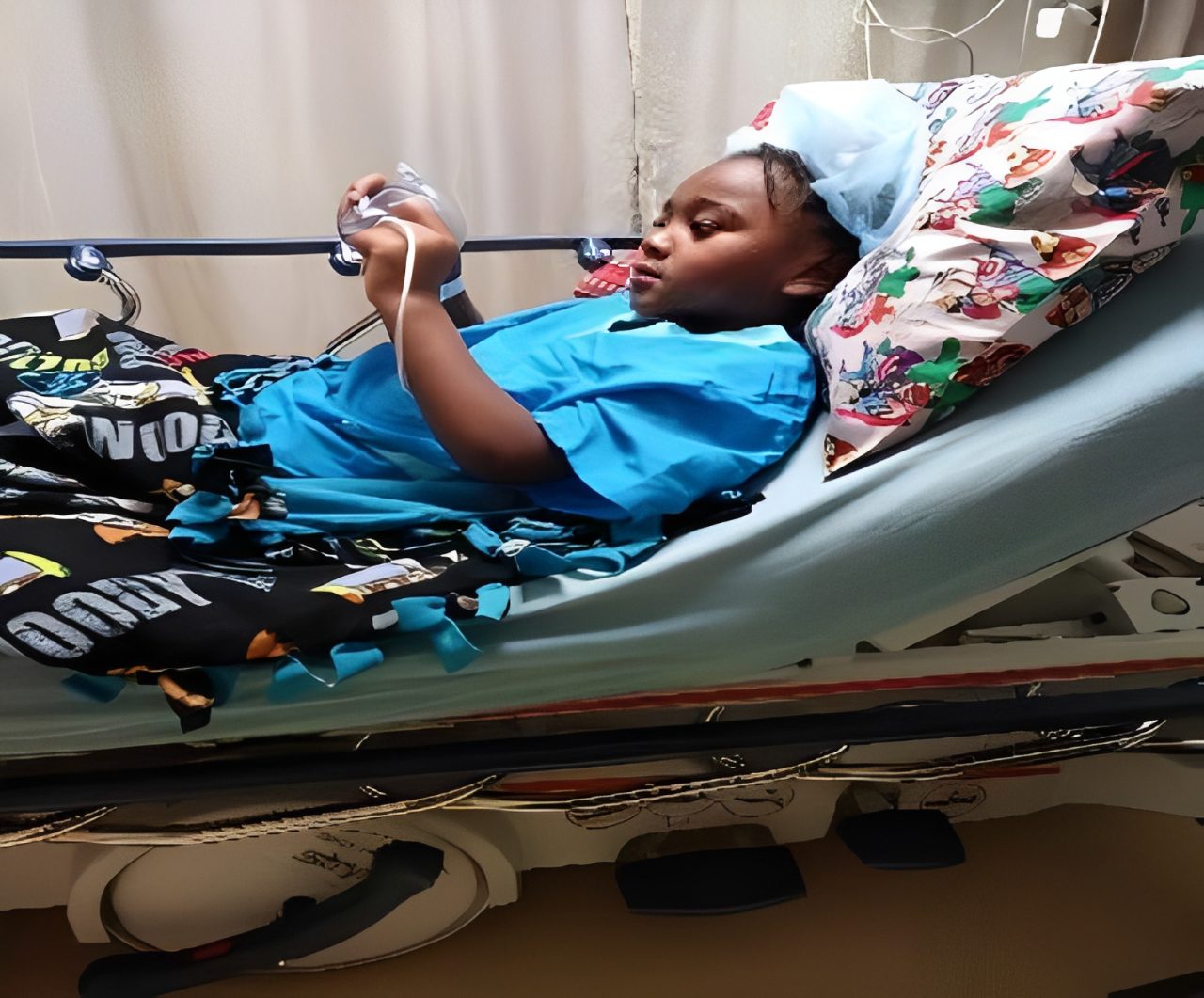 Child patient lying in hospital bed playing on a mobile device.